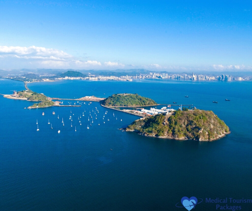 Aerial view of a coastal city with islands, a marina filled with boats, and a distant skyline under a clear blue sky—discover top tourist attractions Panama has to offer for the perfect travel experience.