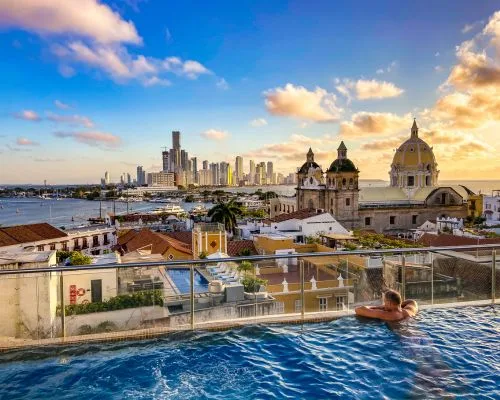 A woman with closed eyes appears superimposed over a cityscape, where a domed building gleams beside a person relaxing in a rooftop pool at sunset—an enchanting invitation to explore the city's tourism packages.