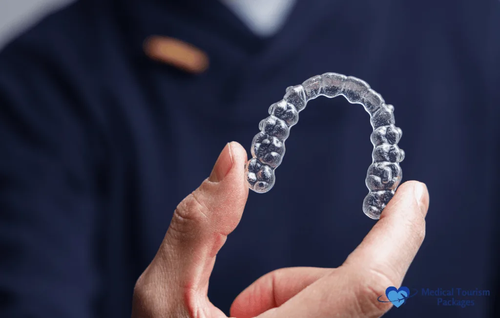Un profesional médico sostiene un retenedor dental de plástico, parte del proceso de corrección de la sonrisa en Colombia. La corrección de la sonrisa en Colombia proporciona atención ortodóncica experta, utilizando retenedores de alta calidad para garantizar resultados duraderos y una sonrisa mejorada para los pacientes.