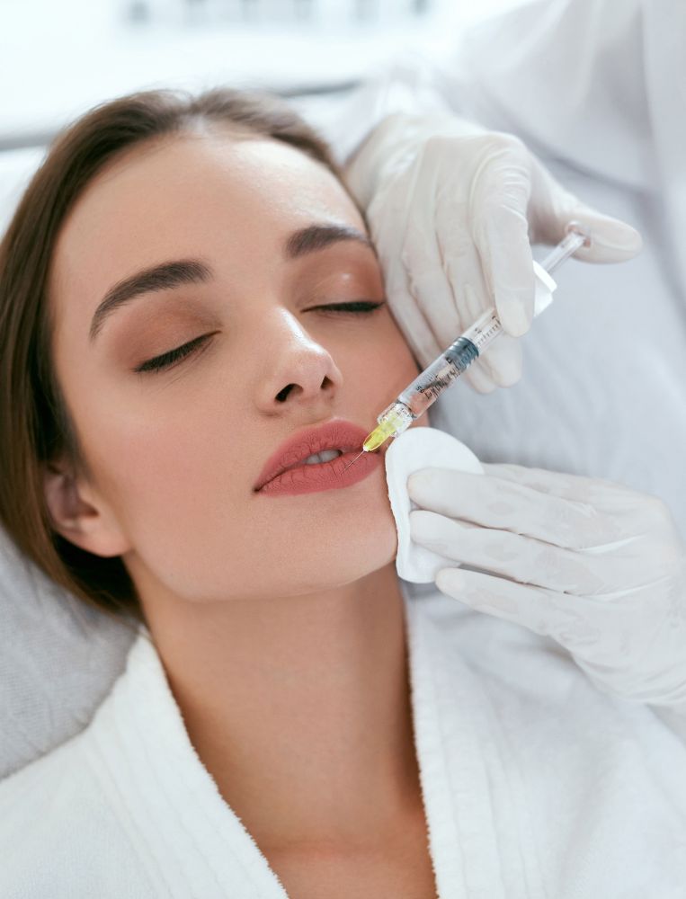 relleno labial Una persona con los ojos cerrados recibe un asequible aumento de labios de un profesional enguantado, tumbado en una camilla y vestido con una bata blanca en América Latina.