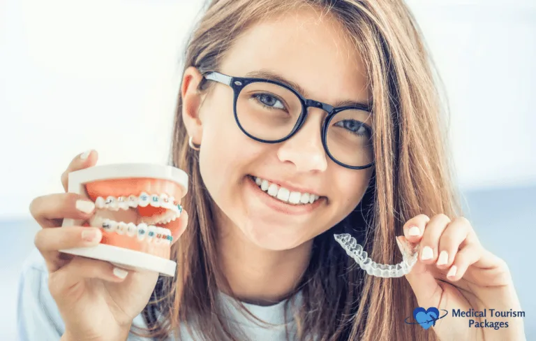 Una chica con gafas sostiene un modelo dental con aparatos en una mano y un alineador transparente en la otra, mostrando los avanzados métodos colombianos de corrección de la sonrisa. Sonríe con confianza, encarnando una guía completa de la ortodoncia moderna.