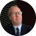 A man wearing glasses and a suit, with a dark background featuring diagonal red and yellow lines.