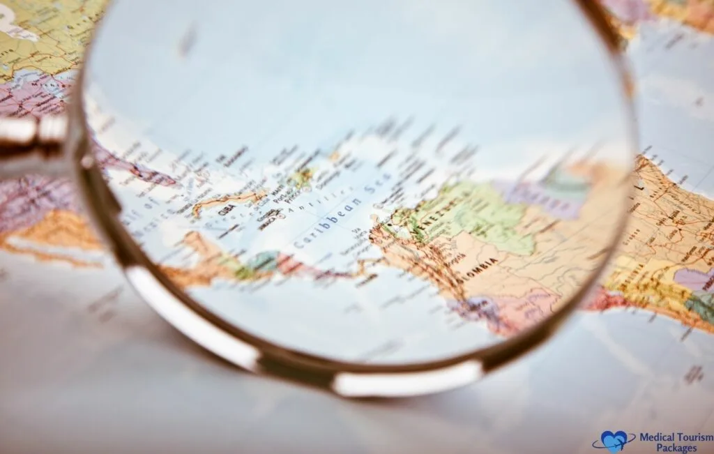 Una lupa sostenida sobre un mapa se centra en el mar Caribe y los países circundantes, ofreciendo una guía paso a paso para planificar su viaje por América Latina.