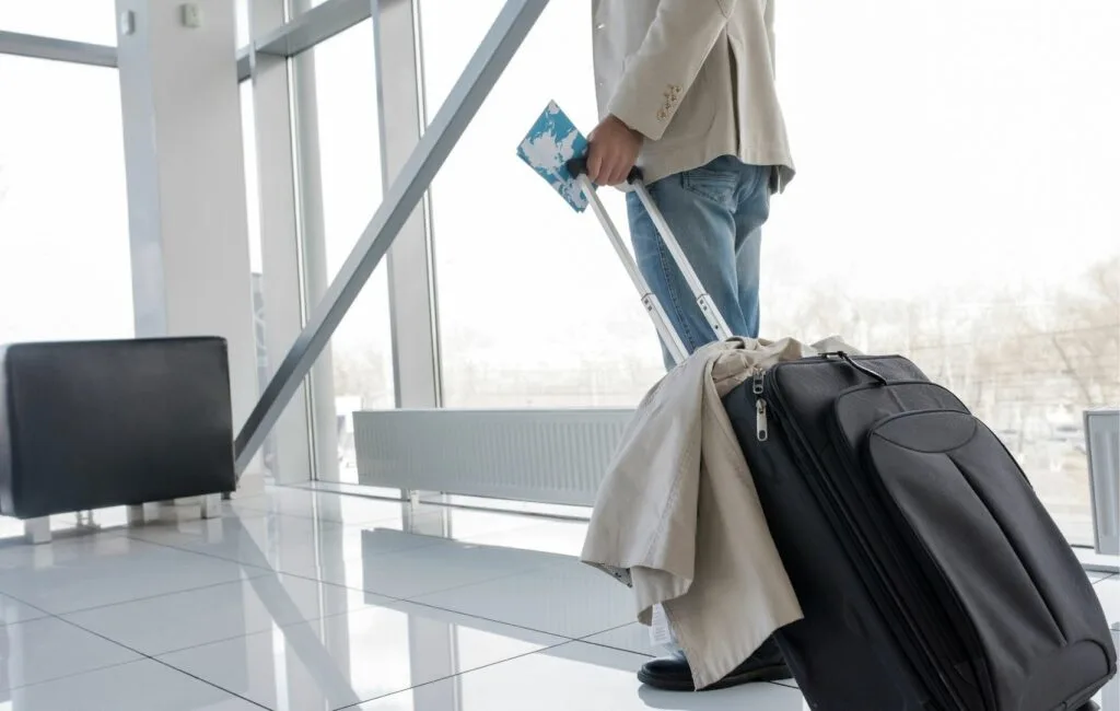 Una persona se encuentra en la terminal de un aeropuerto, con su maleta a mano, su tarjeta de embarque y su abrigo. ¿Su destino? Un emocionante viaje para someterse a una abdominoplastia en Panamá, que combina la promesa de transformación con un toque de aventura.